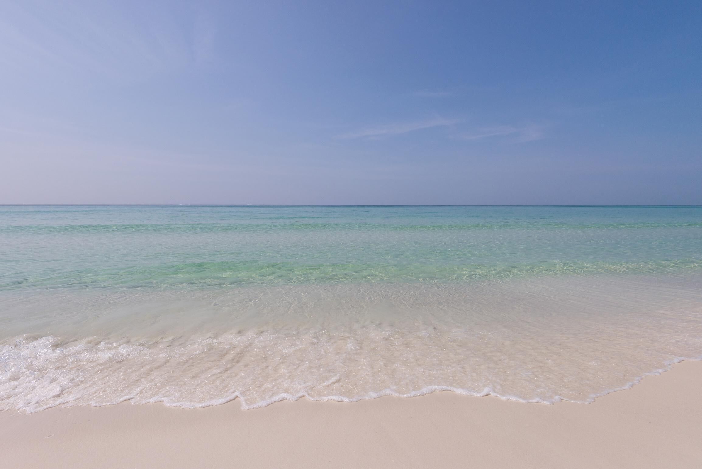A beach with clear turquoise water and a sandy shore.