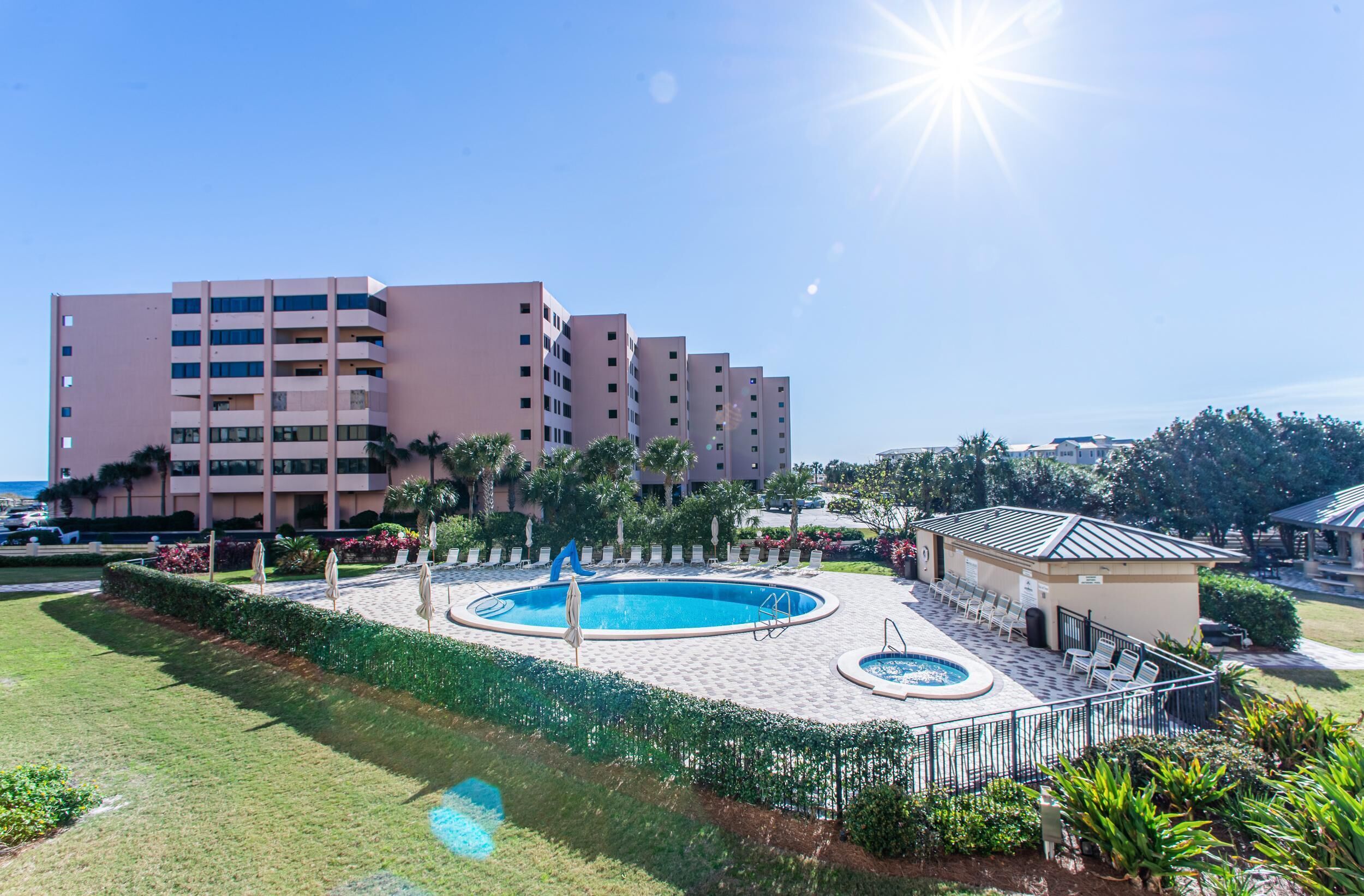 A hotel with a swimming pool, multiple floors, and a landscaped area with palm trees.