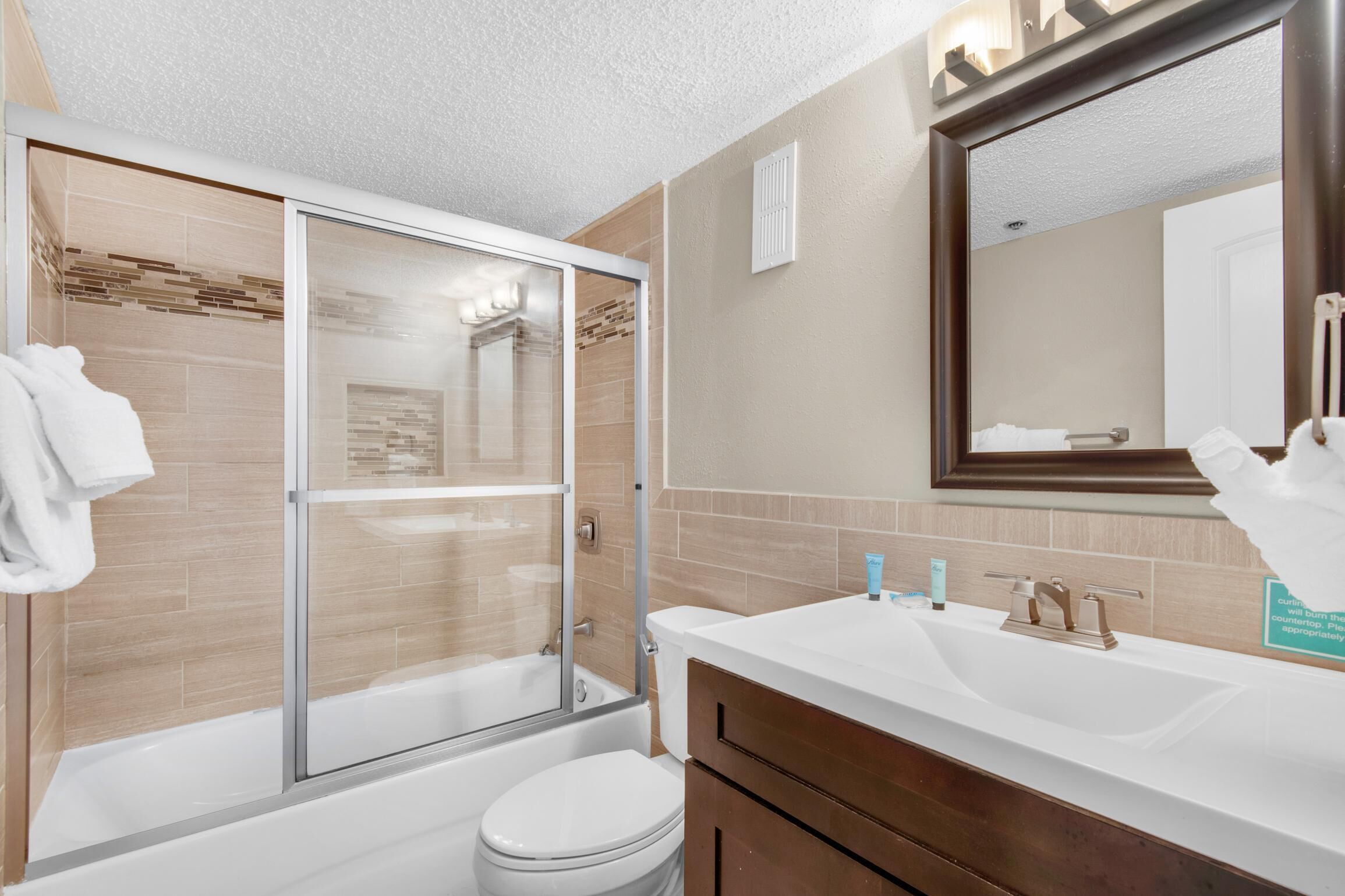 Une salle de bain moderne avec une douche à parois de verre, des toilettes blanches et un meuble-lavabo avec un miroir.