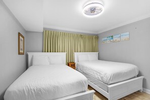 A bedroom with two single beds, a ceiling fan, and a small wooden nightstand. - The Islander 211 (Destin)