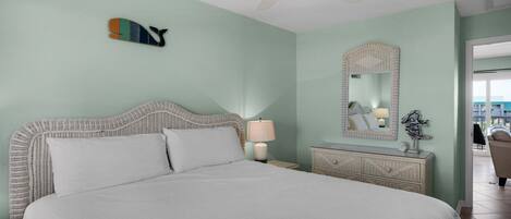 Un dormitorio ordenado con cama, lámpara de noche, cómoda y un espejo de pared.