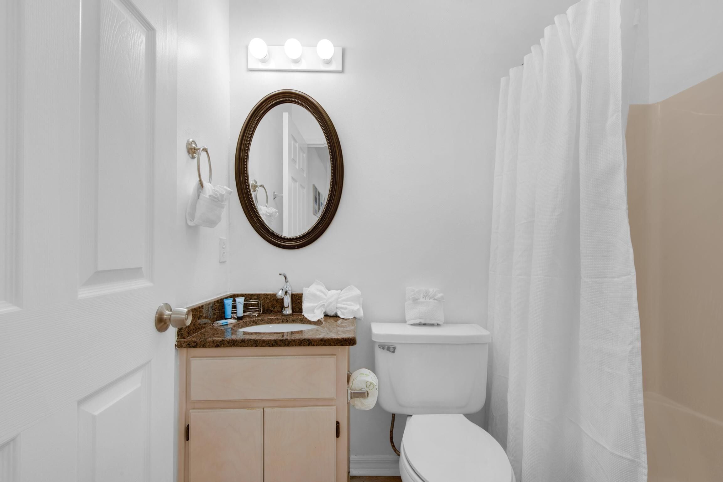 Une salle de bain équipée d’un lavabo, d’un miroir, de toilettes et d’un rideau de douche.