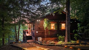 A rustic cabin with a wooden exterior, a porch, and a small garden area with steps leading to the entrance. - Lakefront Getaway, Private Dock, Porch, and Fishing! (Roxboro)