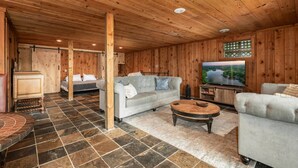 A wooden interior with a sofa, TV, and stone-tiled floor. - Lakefront Getaway, Private Dock, Porch, and Fishing! (Roxboro)