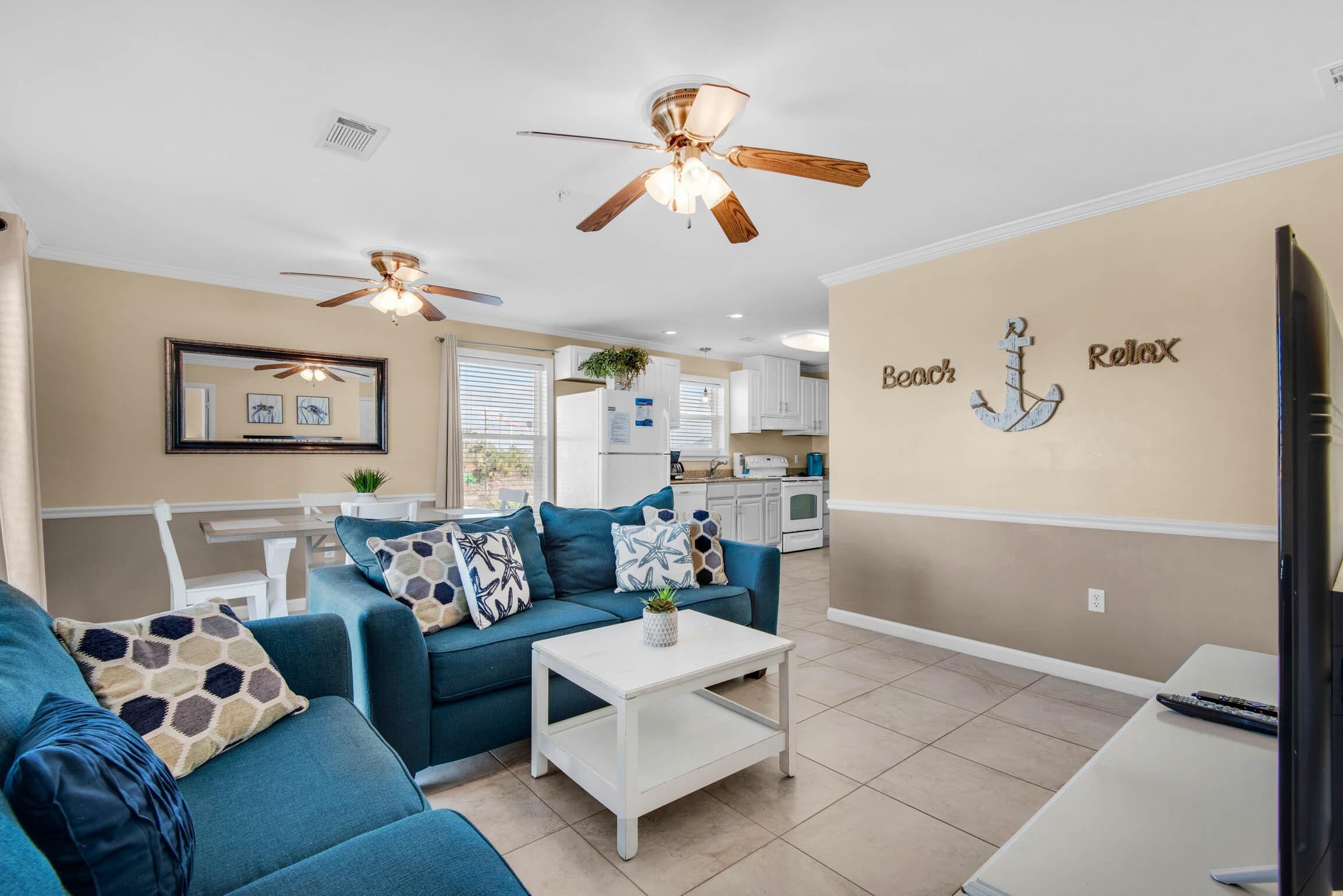 A living room with a blue sofa, white coffee table, and ceiling fans.