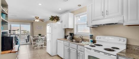 A modern kitchen with white cabinets, a stove, and a dining area with a table and chairs.