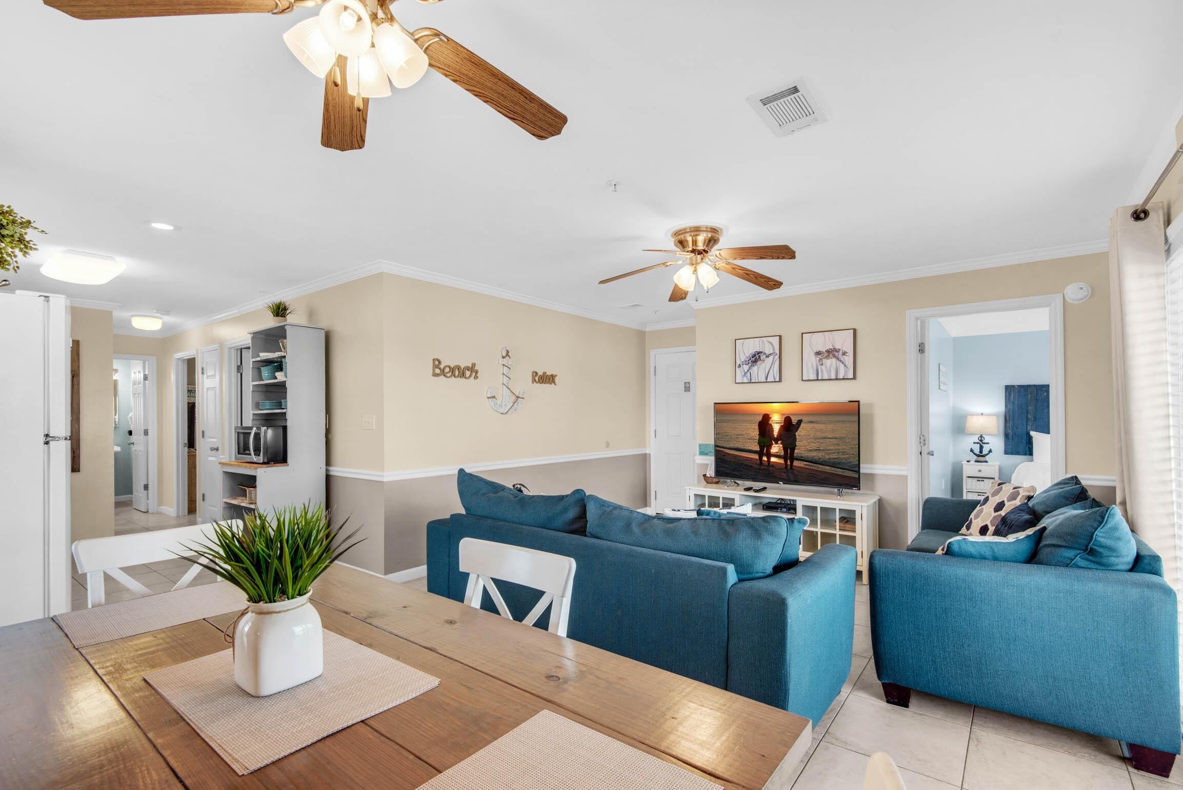 A modern living room with a dining area, featuring a ceiling fan, a TV, and a sofa set.
