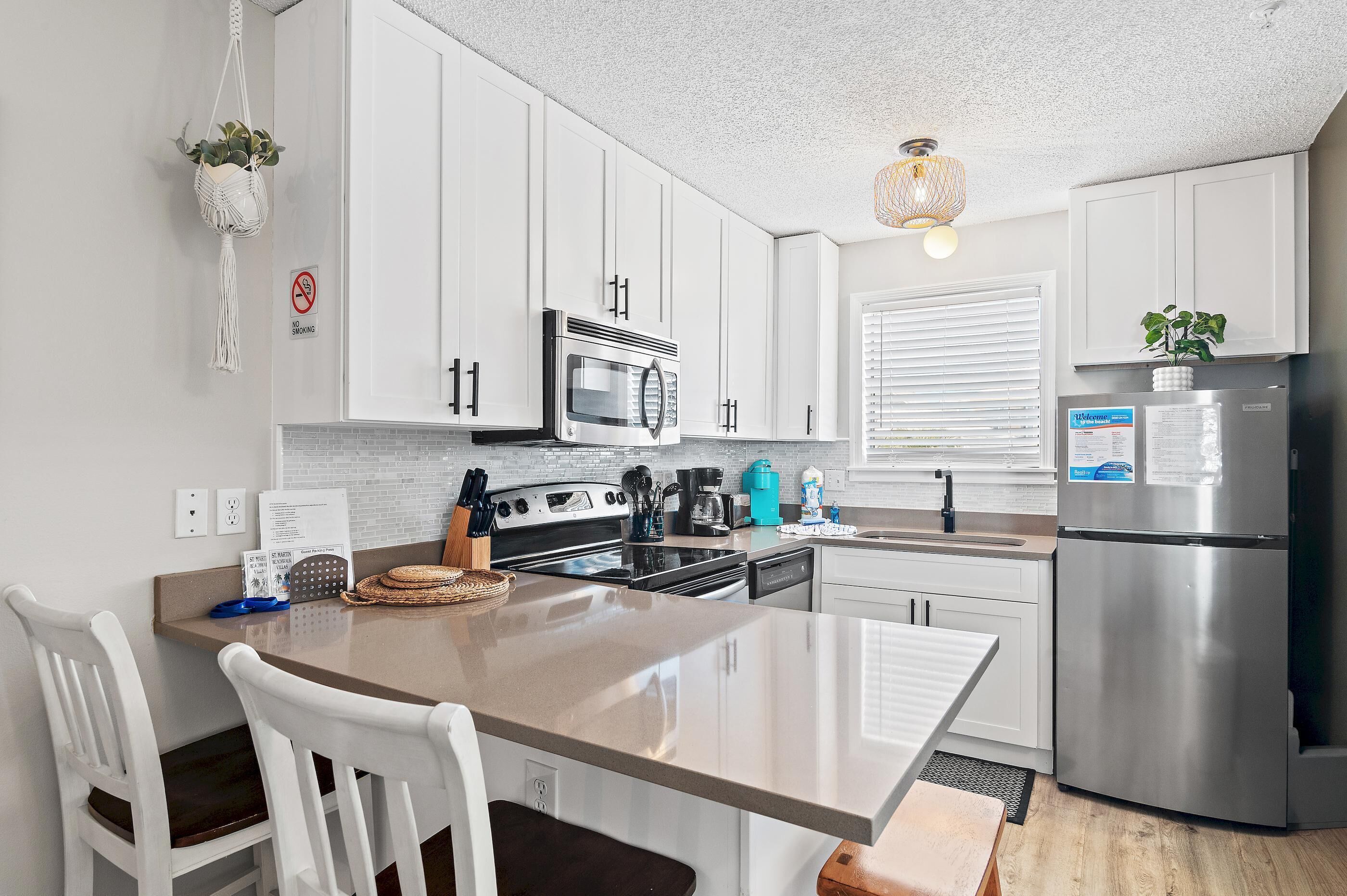 A modern kitchen with white cabinets, stainless steel appliances, and a central island with seating.