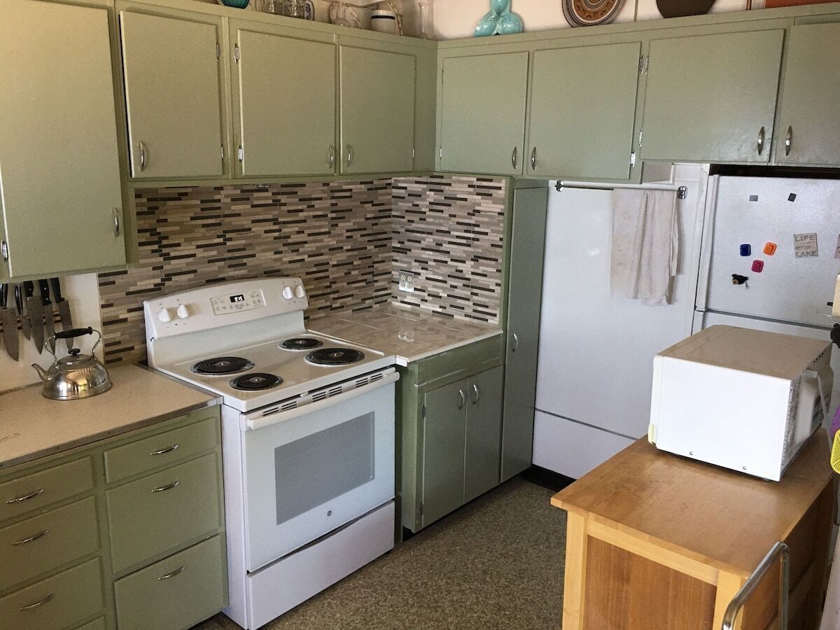 A kitchen with a stove, refrigerator, and cabinets.