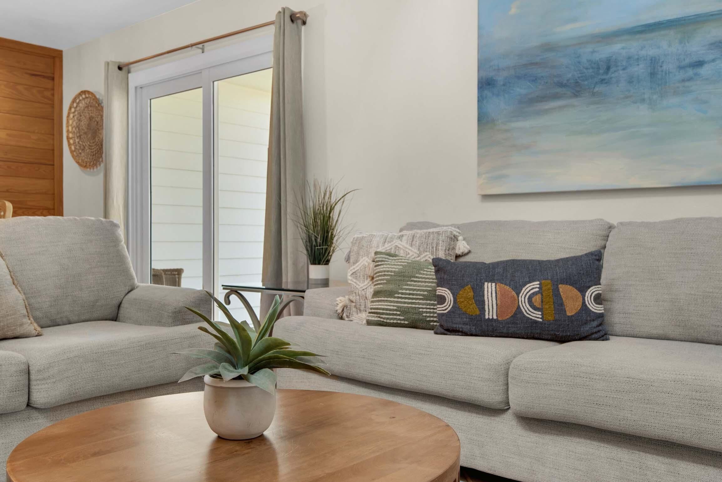 A living room with a sofa, a coffee table, and a potted plant.
