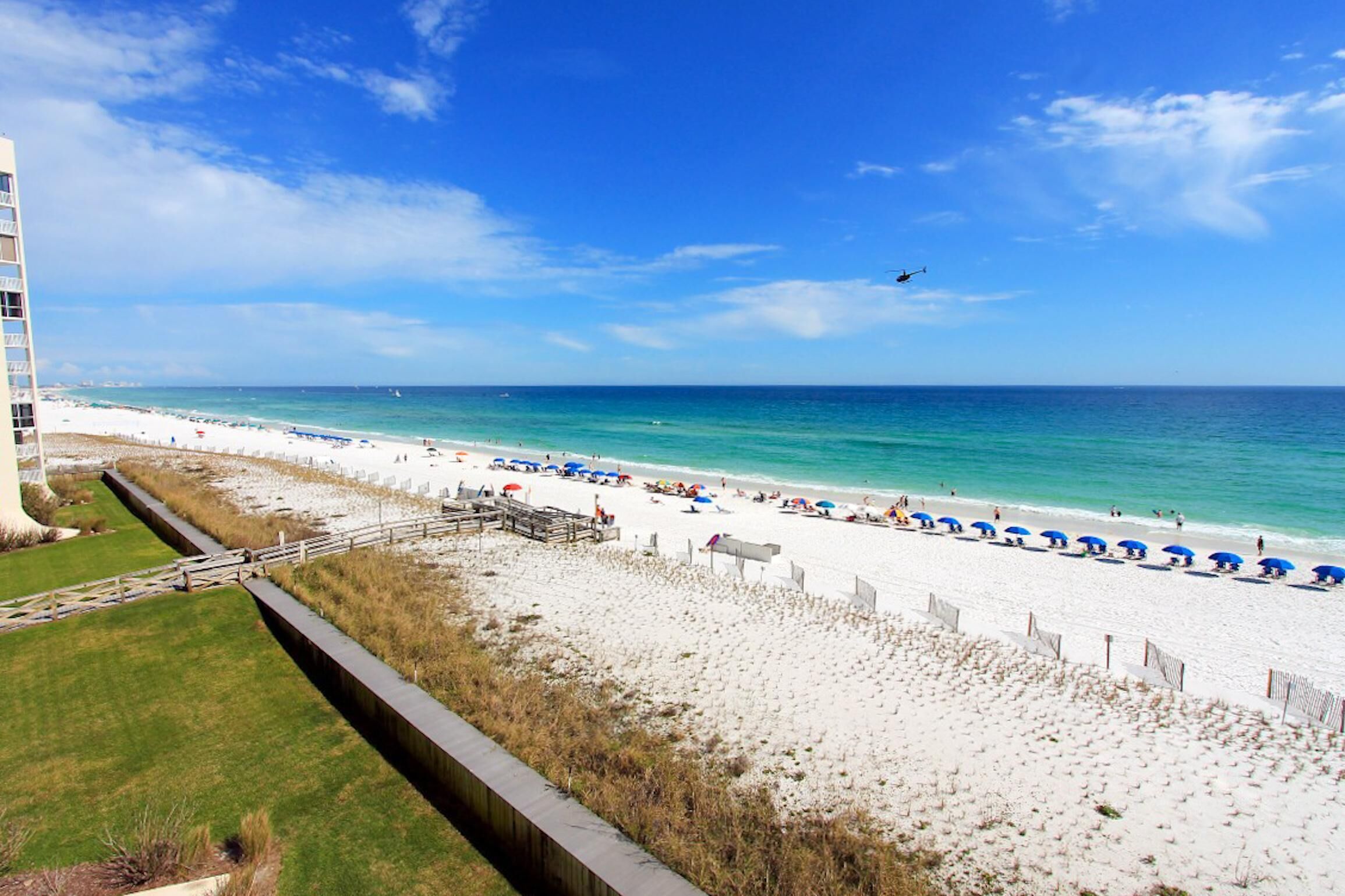 Ein Strand mit blauem Himmel, sandigem Ufer und einem Wasserabschnitt.