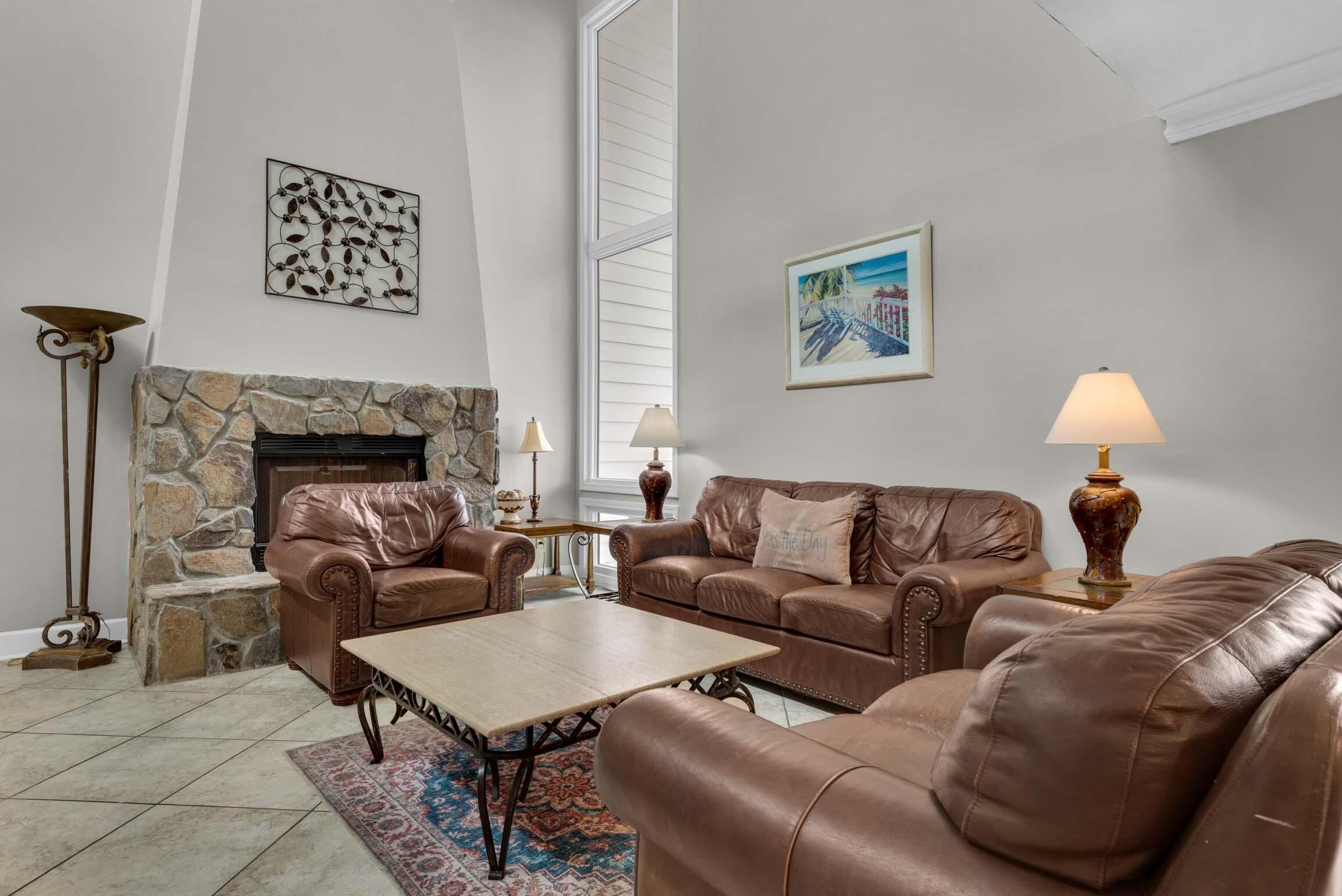 A living room with leather sofas, a stone fireplace, and two lamps.