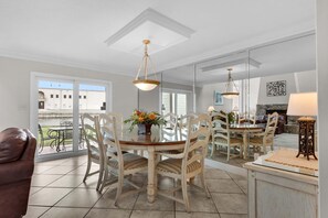 A dining area with a round table, white chairs, and a chandelier. - Shoreline Towers Townhouse 4-3 (Destin)