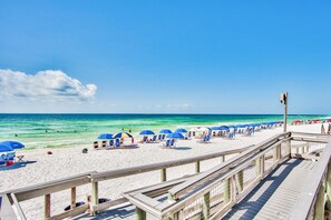 A beach with a wooden boardwalk, umbrellas, and beach chairs. - Shoreline Towers Townhouse 4-3 (Destin)