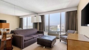 Une chambre d’hôtel moderne dotée d’une grande fenêtre, d’un canapé, d’un bureau et d’une chaise.