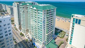 Un hôtel de grande hauteur, avec de nombreux étages, un toit végétalisé et une vue sur la plage.