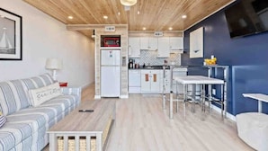 A modern kitchen with white cabinets, a red microwave, and a built-in oven. - Captains Quarters Oceanfront Renovated! Sleeps 4 (Carolina Beach)