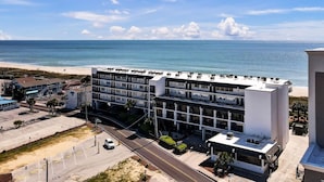 A modern multi-story hotel with a beach view, featuring a parking lot and a road in front. - Captains Quarters Oceanfront Renovated! Sleeps 4 (Carolina Beach)