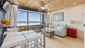 A modern kitchen with a glass dining area, a ceiling fan, and a view of the sea. - Captains Quarters Oceanfront Renovated! Sleeps 4 (Carolina Beach)