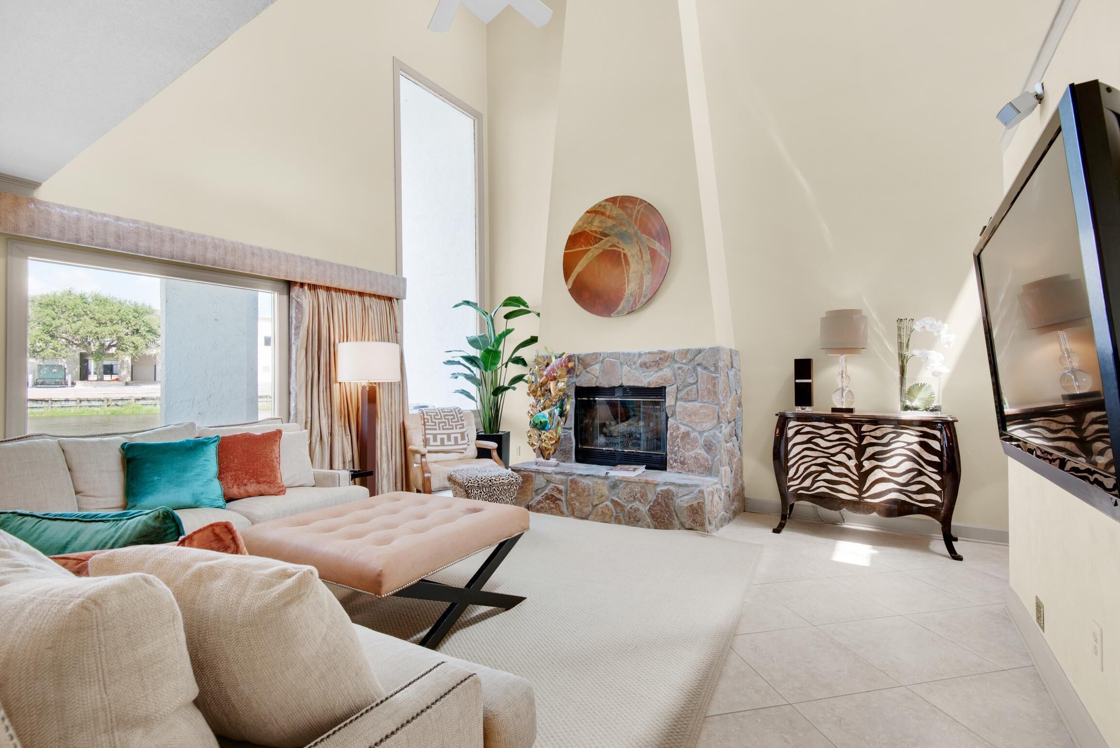 Un salon spacieux avec une cheminée, une grande fenêtre et un canapé moderne.