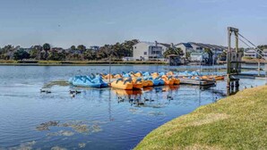 A lake with paddle boats, a dock, and buildings in the background. - Weathertree by the Sea off the Boardwalk Oceanview (Carolina Beach)