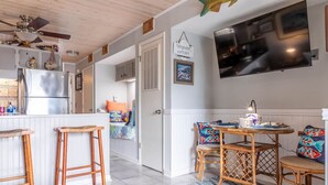 Een moderne keuken met een roestvrijstalen koelkast, houten krukken en een eettafel met kleurrijke kussens.