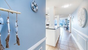A hallway with a light blue wall, a decorative wall hanging, and a large circular artwork. - Shoreline Towers 3073 (Destin)