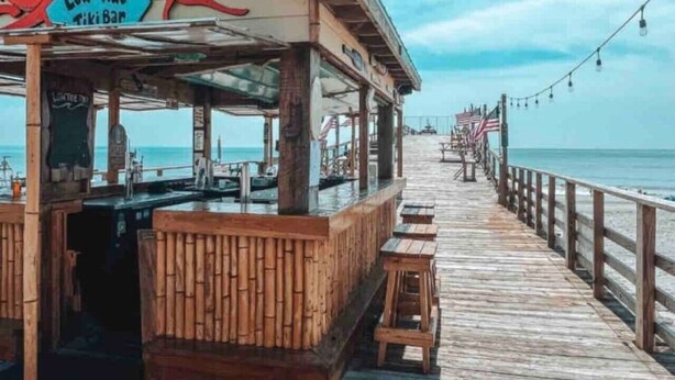 Ein hölzerner Steg führt zu einer Tiki-Bar namens 