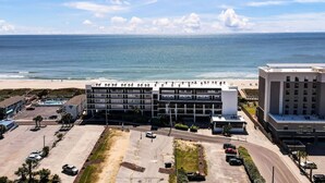 Ein mehrstöckiges Hotel mit Parkplatz und Blick auf den Strand.