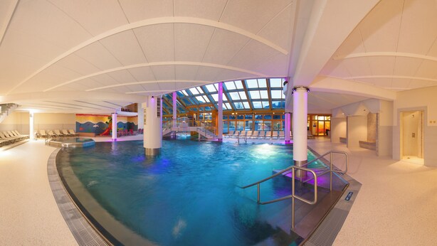 An indoor swimming pool with a glass ceiling, multiple levels, and a children's play area. - Mariengut - Aparthotel Kramer (Wagrain)