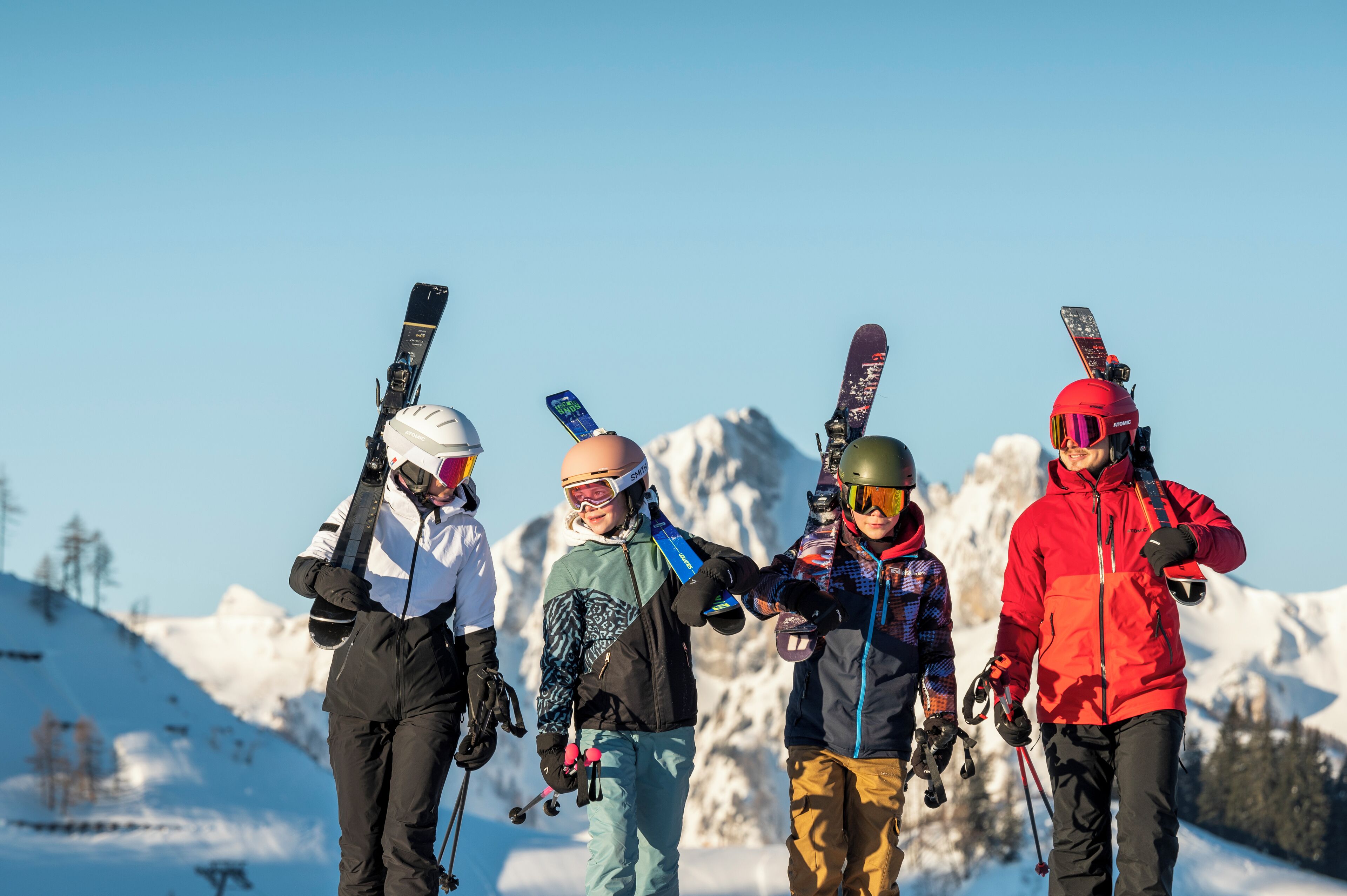 En grupp skidåkare med skidor, stående på en snötäckt sluttning med berg i bakgrunden.