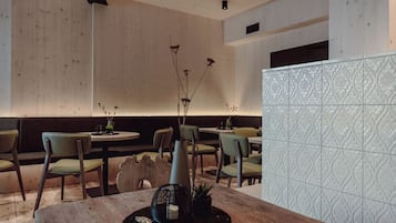 A restaurant interior with wooden walls, green chairs, and a patterned tile backsplash.