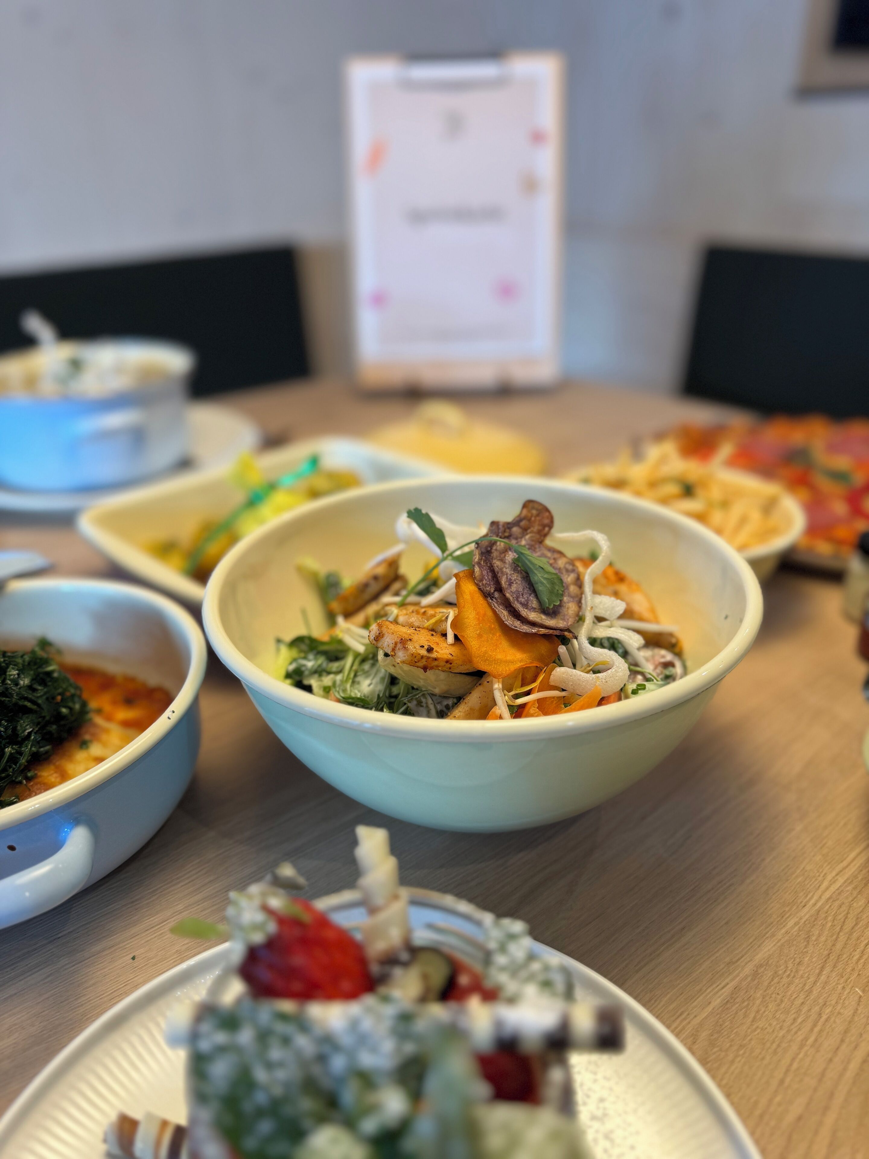 A dining table with various dishes, including a bowl with a mix of vegetables and meat, a plate with a salad, and a bowl of soup.