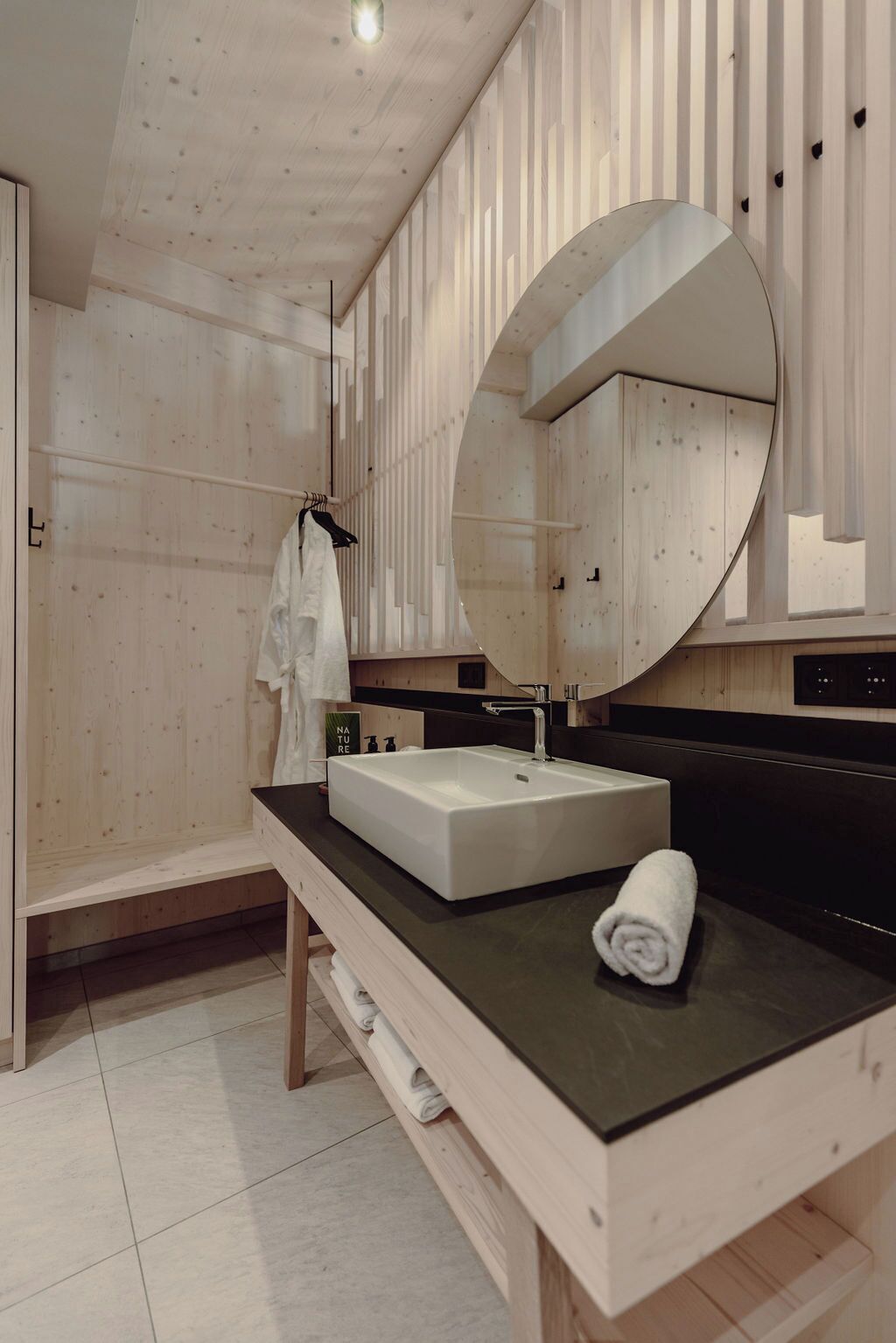 Un baño moderno con tocador de madera, un espejo grande y una toalla sobre la encimera.