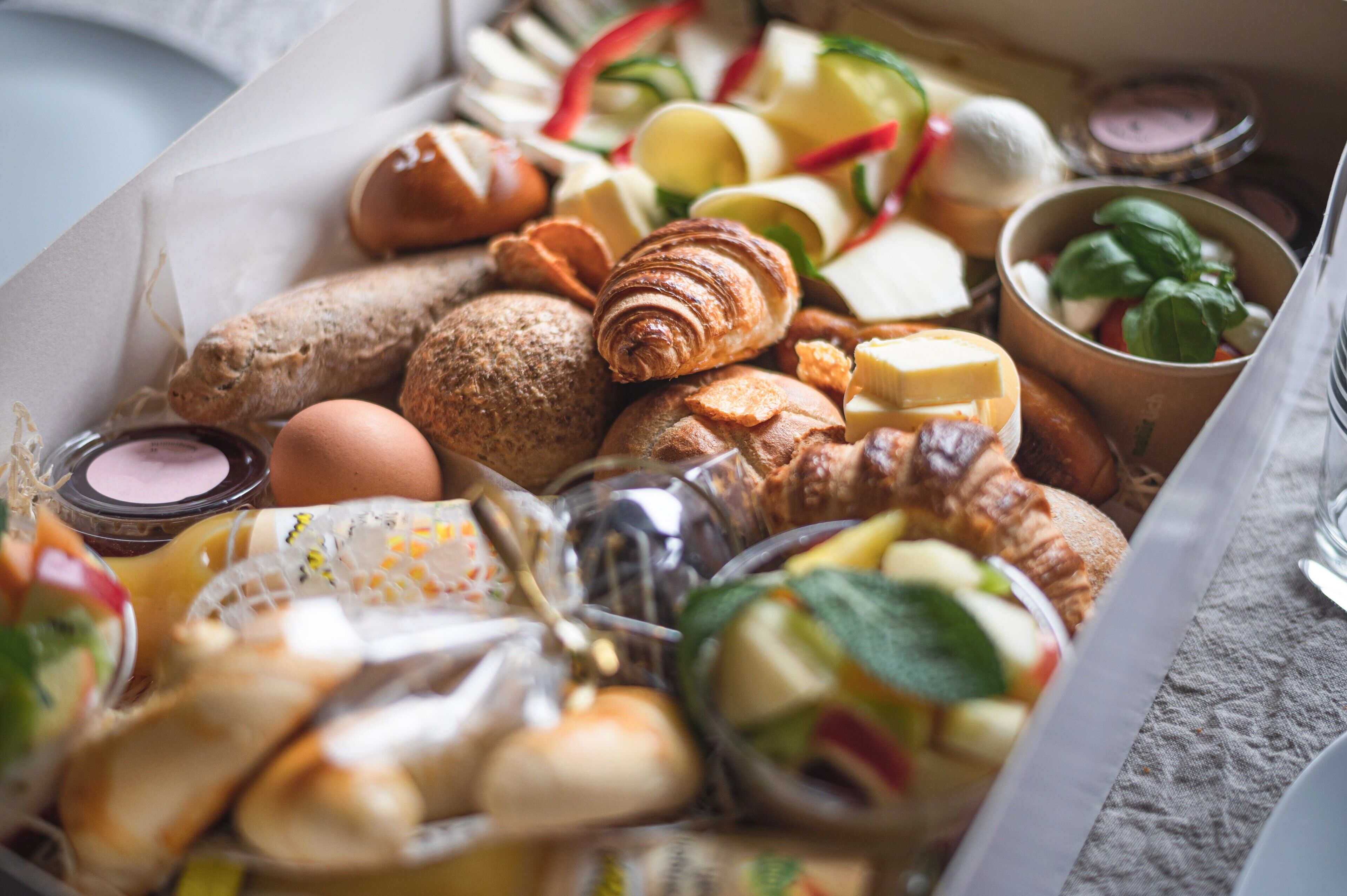Un assortiment de viennoiseries et de fromages, présenté dans une boîte.