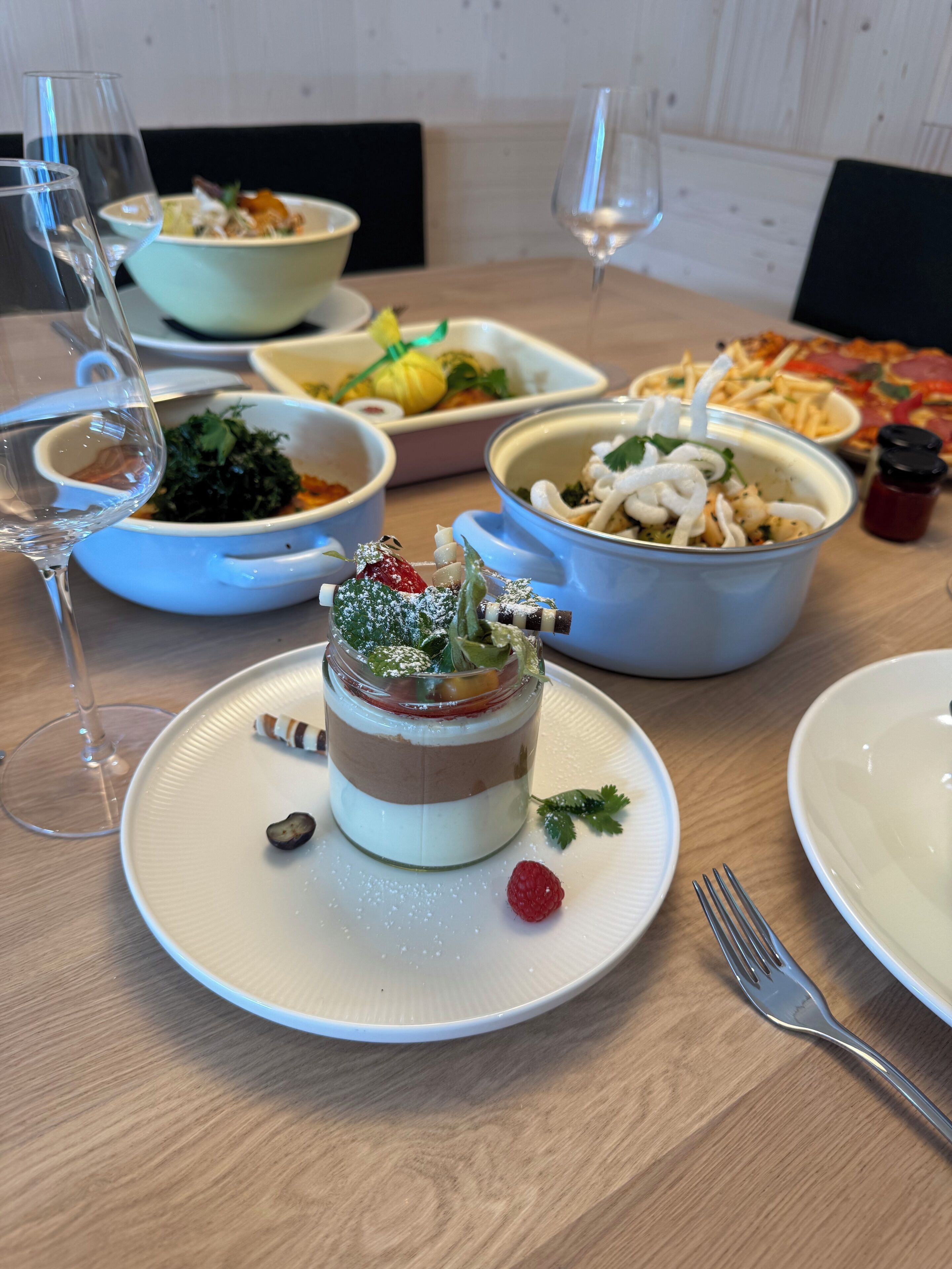 A dining table with various dishes, including a layered dessert, bowls of food, and a pizza.