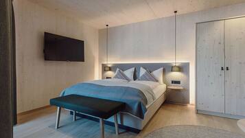 A modern bedroom with a bed, bench, bedside tables, and a wardrobe.