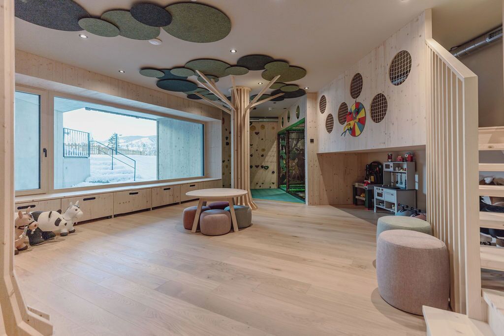 A spacious room with a large window, a play area, and a staircase.