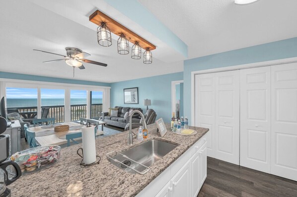A spacious kitchen with granite countertops, a built-in sink, and a ceiling fan.