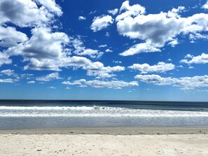 Une plage avec un ciel dégagé et des vagues sur l’océan.
