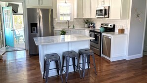 A modern kitchen with white cabinets, stainless steel appliances, and a central island with bar stools.