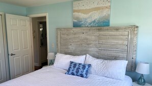 A bedroom with a large bed, a wooden headboard, and a painting above the bed.