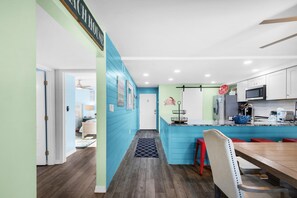 Une cuisine moderne avec des meubles de couleur turquoise, une table à manger en bois et un îlot de cuisine doté de tabourets.