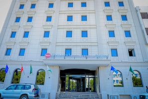 A large, white building with multiple windows and a sign that reads "Premier Residence Hotel".