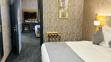A hotel room with a bed, a desk, a television, and a painting on the wall.