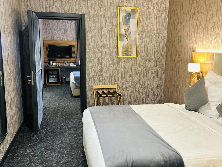 A hotel room with a bed, a desk, a television, and a painting on the wall.