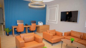 A modern office space with leather sofas, a wooden desk, and a flat-screen TV. - Best Western Premier Dj Hotel (Djibouti)
