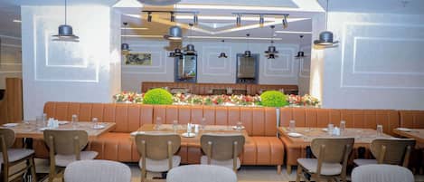A restaurant with booths and tables, modern pendant lighting, and a central floral display.