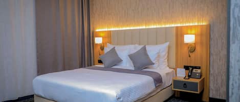 Ein Hotelzimmer mit einem Bett, Nachttischlampen, einem Nachttisch mit Telefon und Teppichboden.