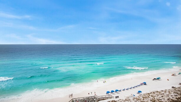 A beach with clear turquoise waters, a sandy shore, and a wooden walkway leading to the beach. - Shoreline Towers 1114 (Destin)